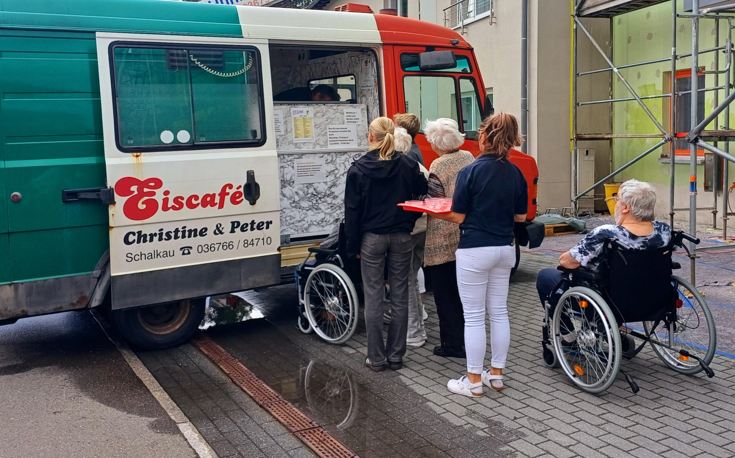 die Bewohner*innen stehen am Eiswagen an und bestellen ihr Eis